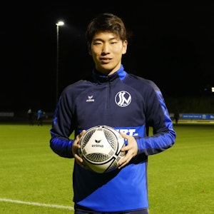 Kaito Asano vom Siegburger SV 04 steht mit einem Fußball in der Hand am Spielfeld.