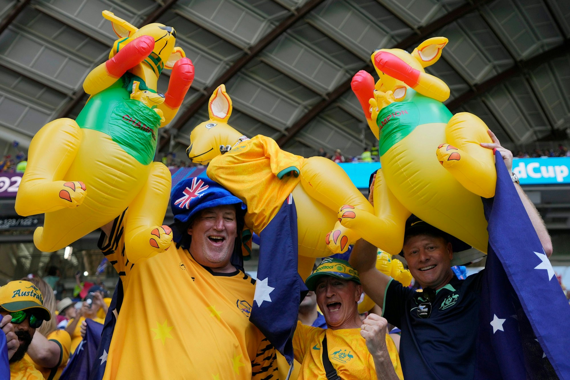 Drei Australien-Fans halten ihre aufblasbaren Kängurus im Stadion in die Luft und jubeln dabei.