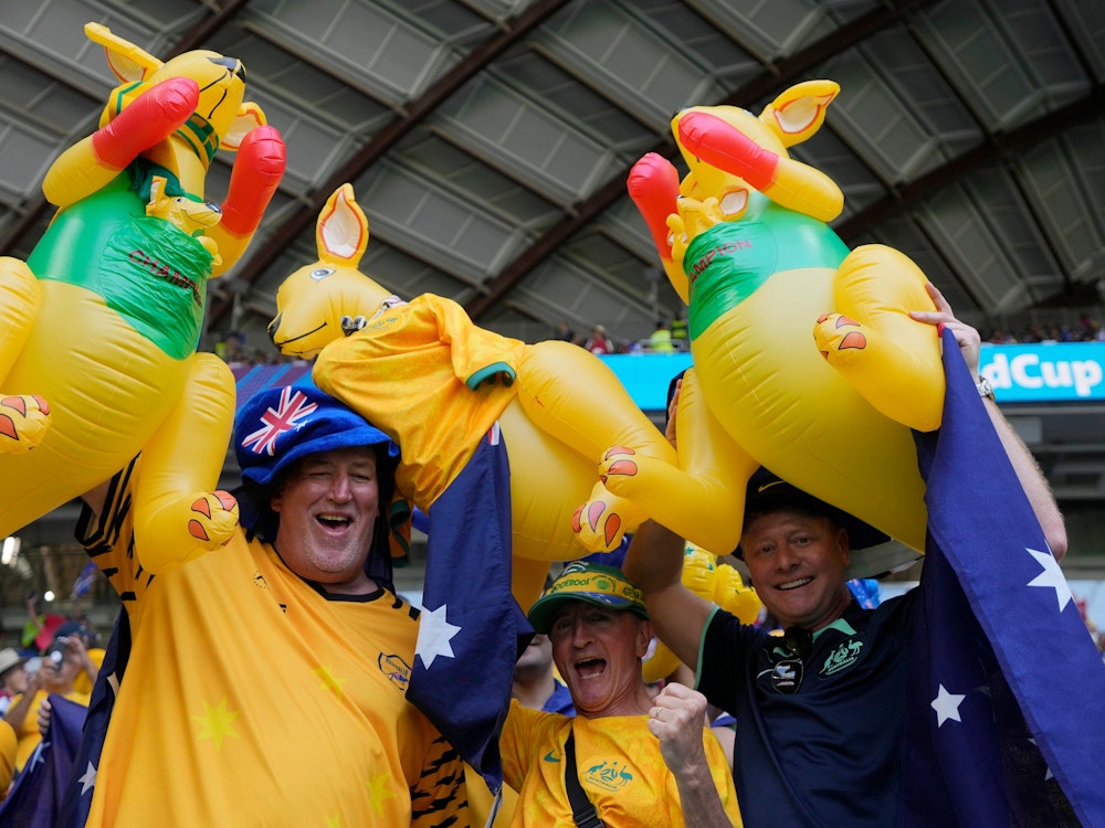 Drei Australien-Fans halten ihre aufblasbaren Kängurus im Stadion in die Luft und jubeln dabei.