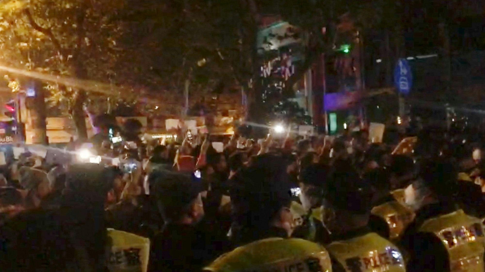 In diesem Bild aus einem Video, das The Associated Press erhalten hat, beobachtet die Polizei (im Vordergrund) die Demonstranten in Shanghai.