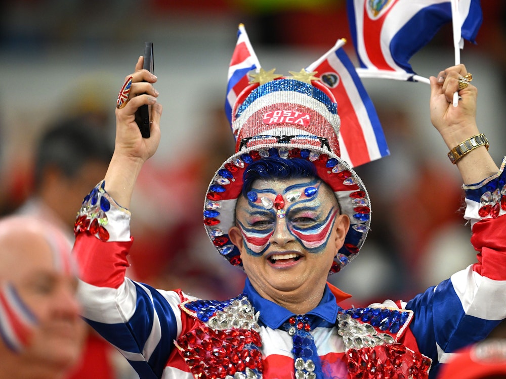 Eine Dame, die scheinbar Costa-Rica-Fan ist, steht auf der Tribüne, mit einem Hut und aufwendiger Bemalung im Gesicht.