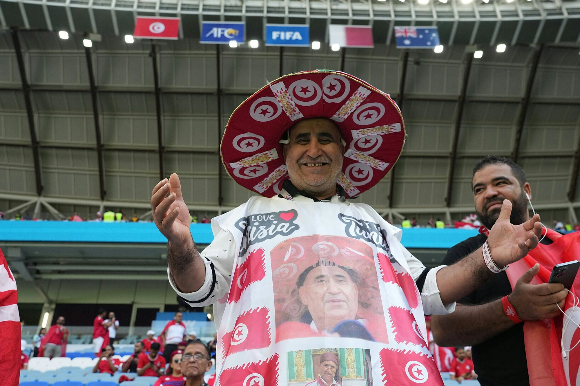 Ein tunesischer Fan mit Sombrero und einem Gewand zeigt sich lächelnd auf der Tribüne.