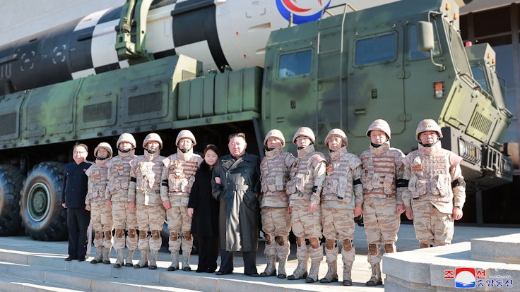 Nordkoreas Machthaber Kim Jong-un posiert mit Soldaten und seiner Tochter vor einer Rakete.