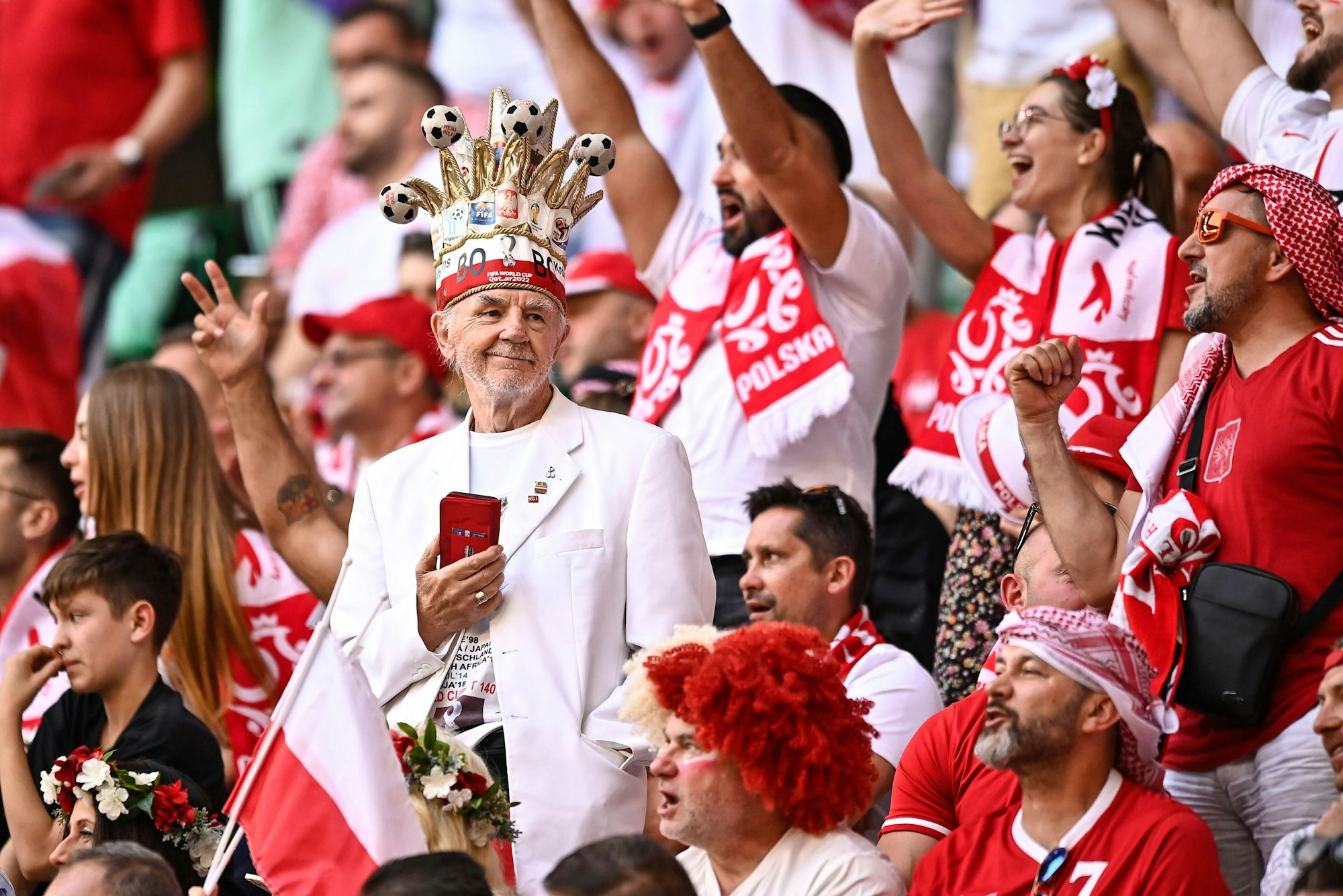 Ein Polen-Fan mit weißem Anzug und Fußball-Krone auf der Tribüne beim Spiel gegen Saudi-Arabien.