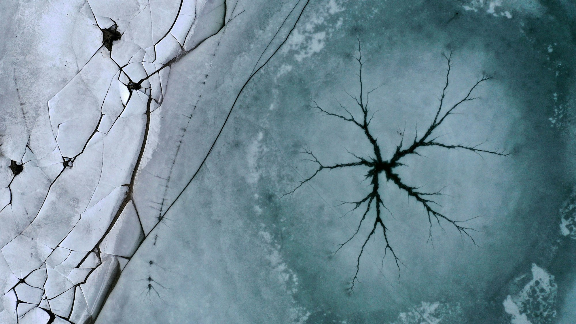 Bayern: Ein sternförmiger Riss ist auf der Eisfläche des Forggensees neben am Ufer liegenden gebrochenen Eisplatten zu sehen.