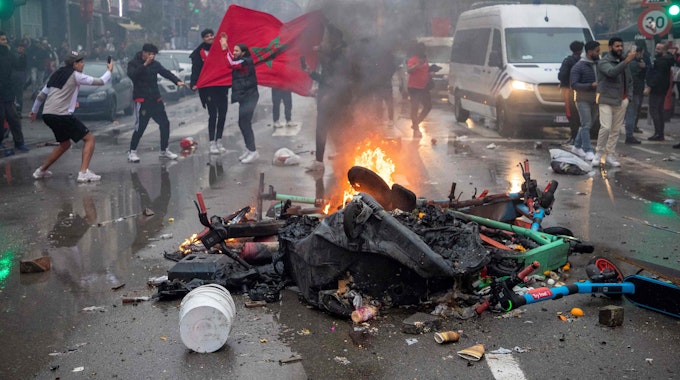 Fußball-Fans stehen in Brüssel neben einer brennenden Straßen-Barrikade.
