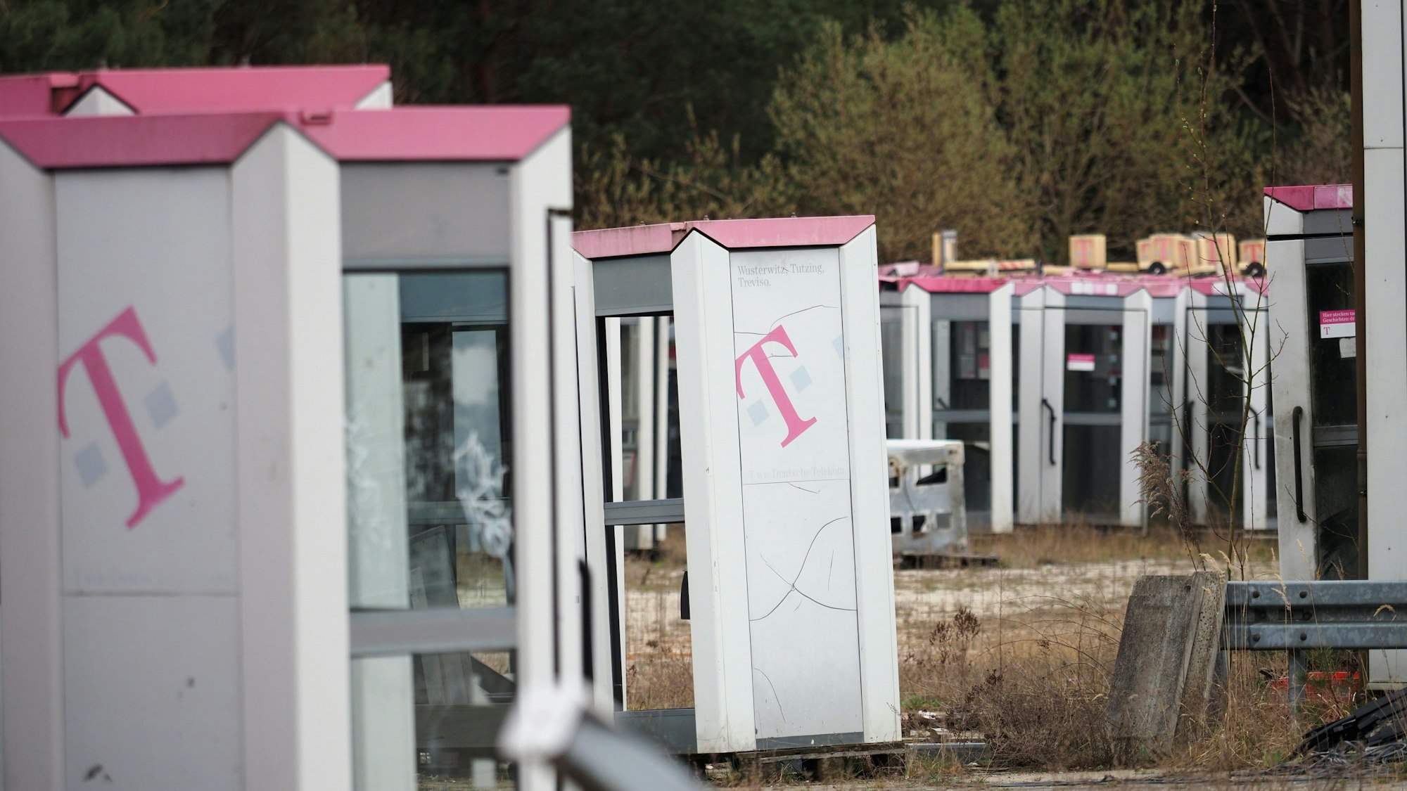 Ausrangierte Telefonzellen stehen auf einem abgezäunten Gelände in Brandenburg.