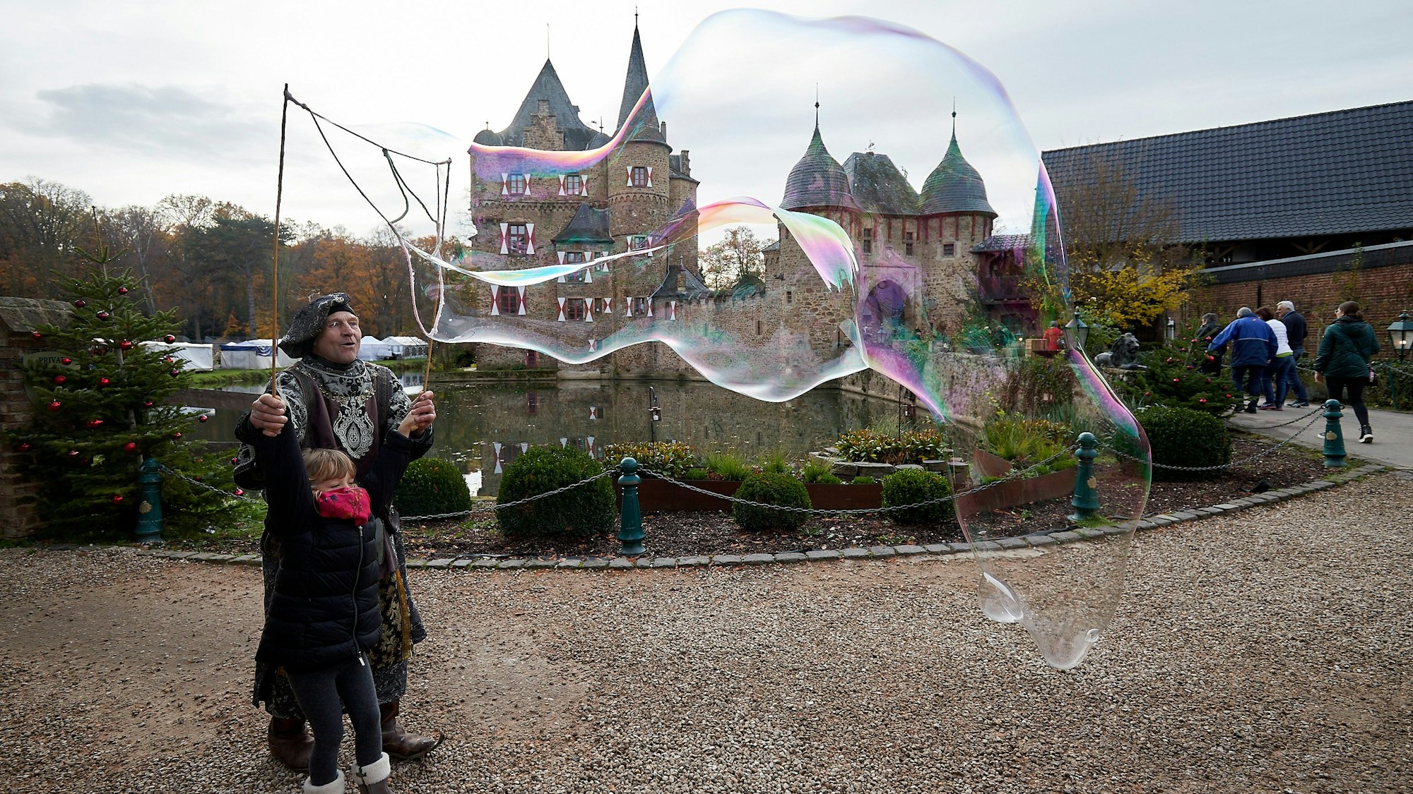 Die fünfjährige Ada Crispi erstellt mithilfe des Gauklers Alfred Schönfelder von Burg Satzvey Riesenseifenblasen.