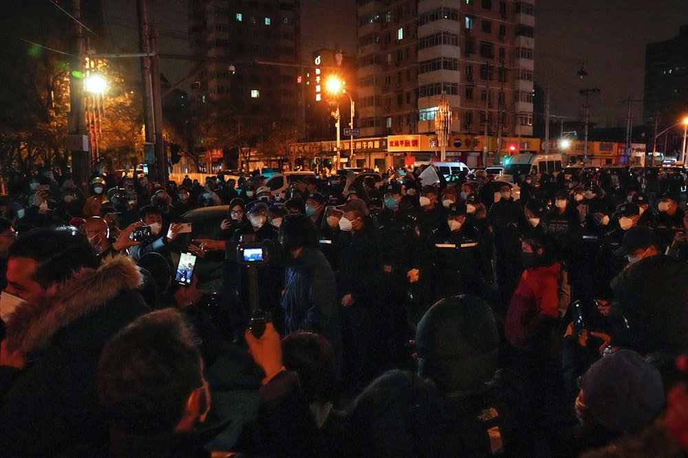 Demonstrierende stoßen mit Polizisten während einer Demonstration zusammen. In China hat die strenge Corona-Politik am Wochenende zu den größten Protesten seit Jahrzehnten geführt.
