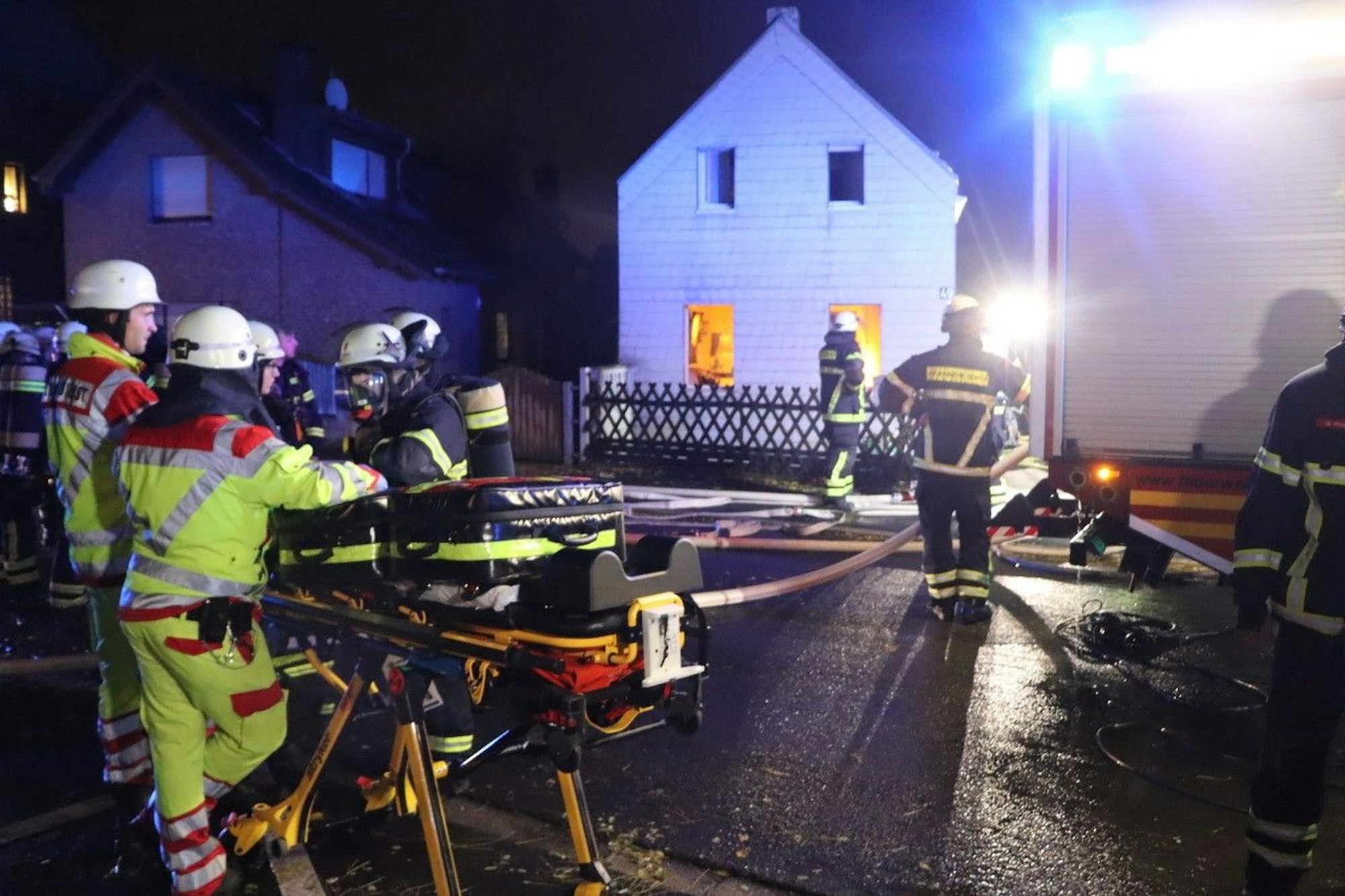 Sanitäter und Feuerwehrleute stehen an dem brennenden Haus in Hürth.
