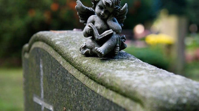 Eine Engelsfigur sitzt auf einem Grabstein und befindet sich auf dem Trinitatsfriedhof in Dresden (Symbolbild).