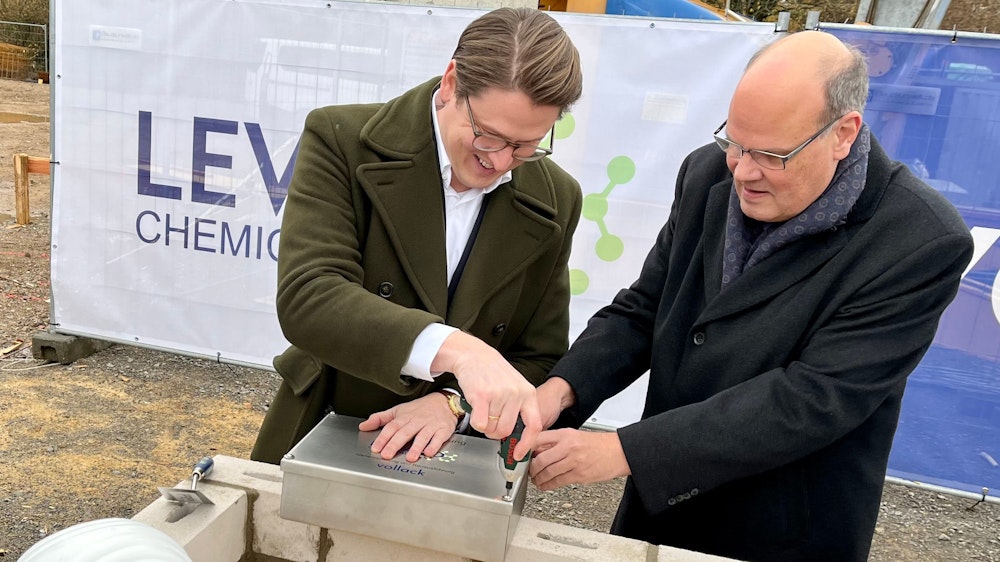 Marius Mühlenberg, CEO von Levaco, schraubt mit Finanzchef Jens Becker an der Metallkiste, die in den Grundstein gelegt wird.