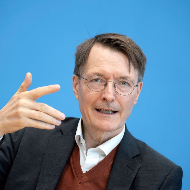 Gesundheitsminister Karl Lauterbach im Anzug vor einem blauen Hintergrund.