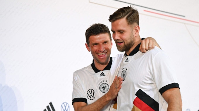 Die Nationalspieler Thomas Müller (r.) und Niclas Füllkrüg (l.) auf dem Weg zur Pressekonferenz der deutschen Nationalmannschaft in Doha. Müller schüttelt Füllkrug an den Schultern durch.