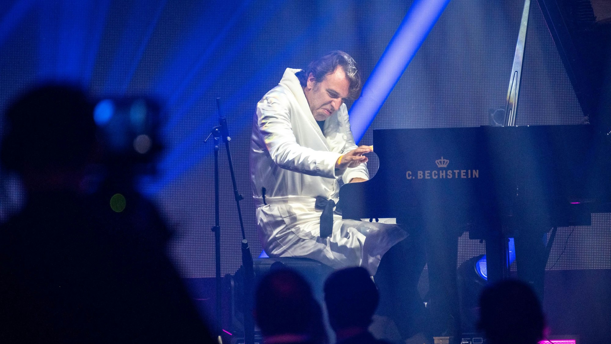 Der Kölner Musiker Chilly Gonzales sitzt in weißen Bademantel am Klavier und hämmert wuchtig in die Tasten.