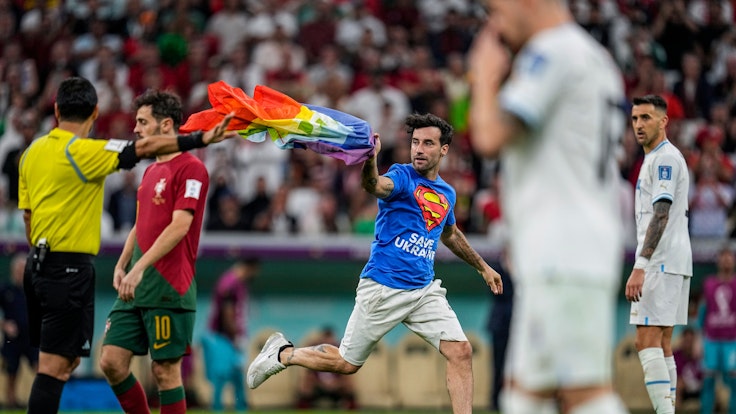 Ein Flitzer mit Regenbogenfahne sorgte für eine Unterbrechung des WM-Spiels zwischen Portugal (hier mit Bernardo Silva im roten Trikot) und Portugal (rechts mit Matias Vecino) am 28. November 2022. Links: Schiedsrichter Alireza Faghani, der die Fahne später aufhob.