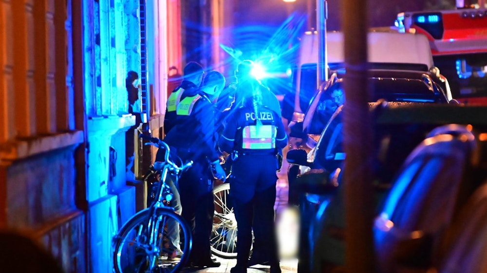 Polizisten stehen auf einem Gehweg neben dem Toten. In der Krefelder Innenstadt ist am Montagabend ein Mann auf offener Straße erschossen worden.