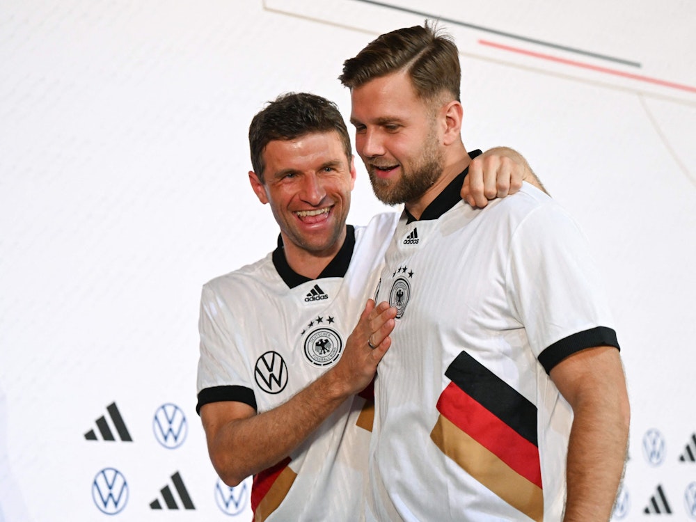 Thomas Müller und Niclas Fuellkrug scherzen nach der Pressekonferenz miteinander.