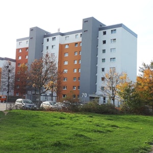 Ein grau-orangefarbener Wohnblock steht am Rande einer Rasenfläche.