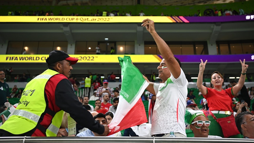 Ein Security-Mitarbeiter konfisziert bei der WM 2022 in Katar eine Flagge des Iran, auf der das Symbol der Islamischen Republik ausgeschnitten ist.