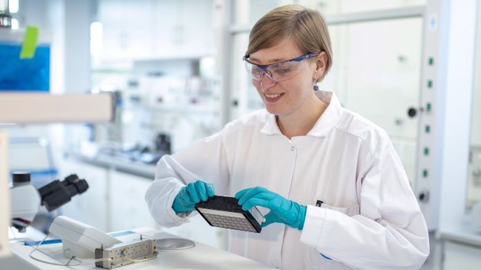 Lena Schaffert steht im weißen Kittel im neuen Labor des Kompetenzzentrums für Biotechnologie.