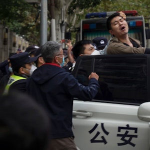 Auf diesem Foto vom Sonntag, 27. November 2022, reagiert ein Demonstrant, als er während einer Demonstration auf einer Straße in Shanghai, China, von Polizisten verhaftet wird.