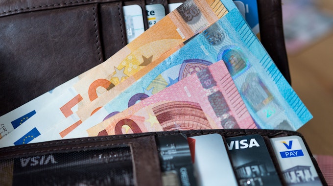 Banknoten und Bankkarten liegen in einer Geldbörse.