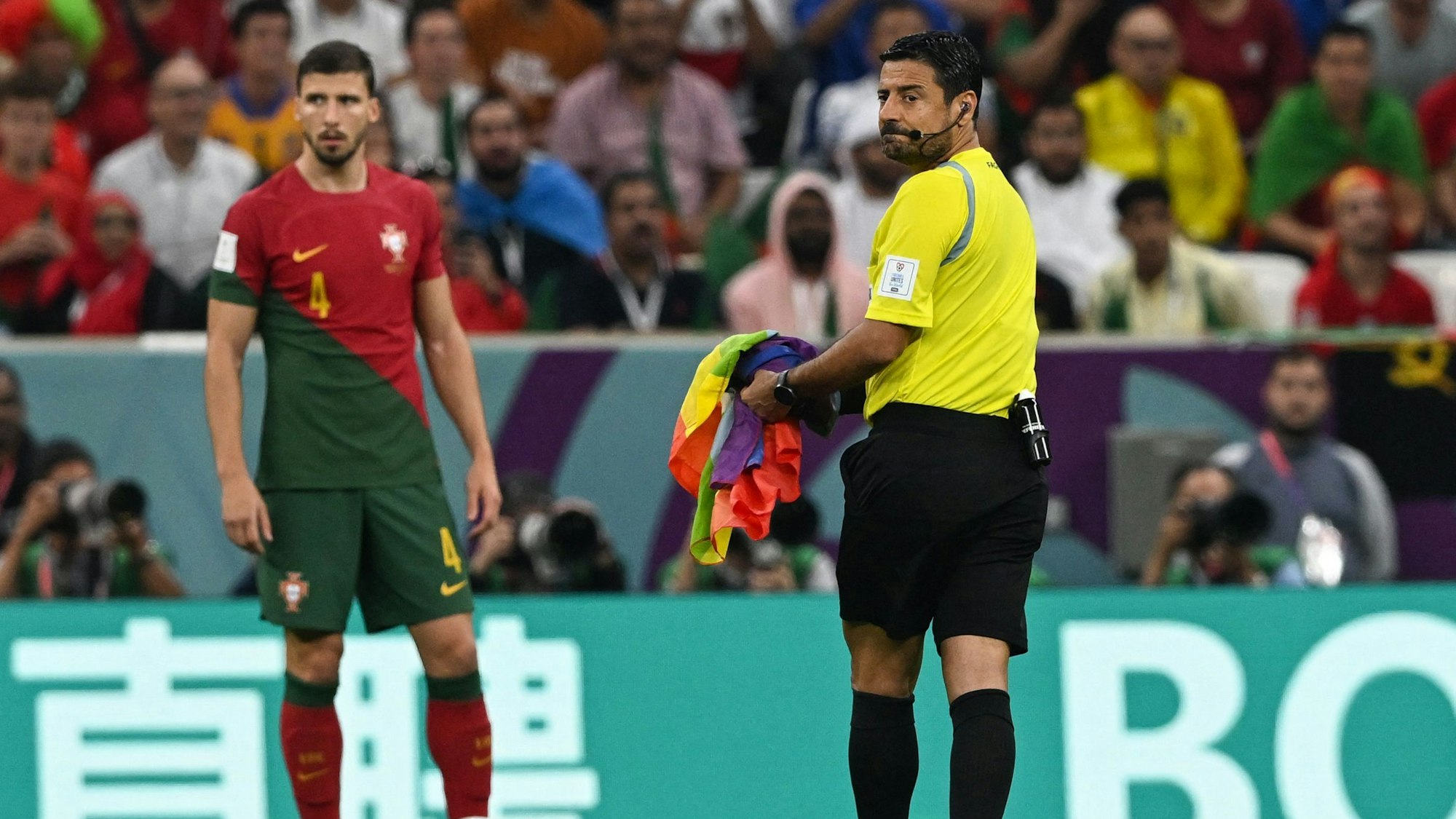 Beim Spiel Portugal gegen Uruguay hat ein Flitzer eine Regenbogenfahne vor den Füßen des Schiedsrichters fallen lassen. Der hebt sie auf und bringt sie an den Spielfeldrand.