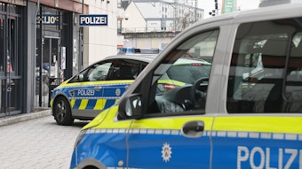 Zwei Polizeifahrzeuge stehen vor einer Polizeiwache.