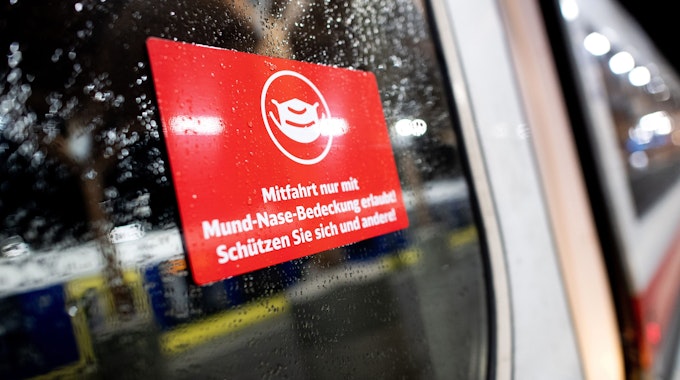 Ein Schild mit der Aufschrift „Mitfahrt nur mit Mund-Nase-Bedeckung erlaubt! Schützen Sie sich und andere!“ - klebt an der Tür eines Zuges der Deutschen Bahn.