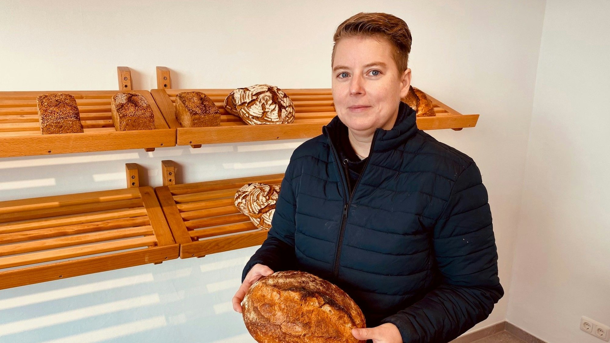 Die neue Inhaberin hält ein Brot in der Hand.