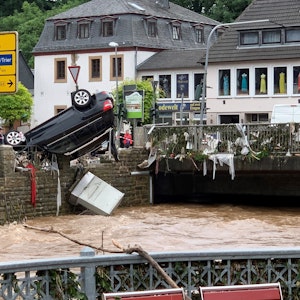 Nach dem Hochwasser am 14. Juli 2021 hängt ein Auto kopfüber an einem Geländer in Gemünd.