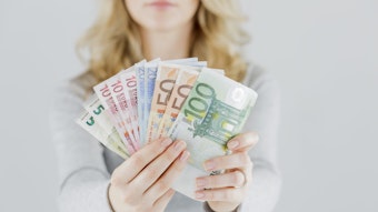 Eine Frau hält verschiedene Geldscheine in die Kamera, von fünf bis 100 Euro.