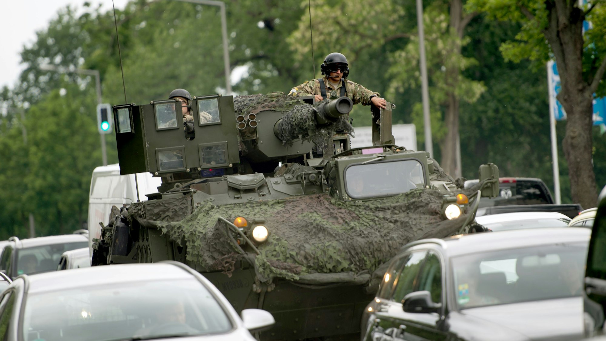 Ein Panzer der US-amerikanischen Streitkräfte ist auf einer Straße unterwegs. Ein Soldat mit Sonnenbrille sitzt auf dem Geschützturm. Um den Panzer herum fahren Autos (Symbolbild)