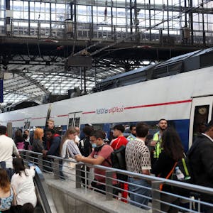 Fahrgäste warten auf Gleis 4 am Kölner Hauptbahnhof auf einen Zug von National Express. Einige Fahrgäste steigen aus, andere in den Zug ein. (Symbolbild)