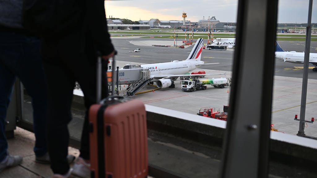Eine Frau steht im Oktober 2022 mit ihrem Koffer auf der Aussichtsplattform und schaut auf das Flugfeld vor dem Terminal 1 am Hamburger Airport.