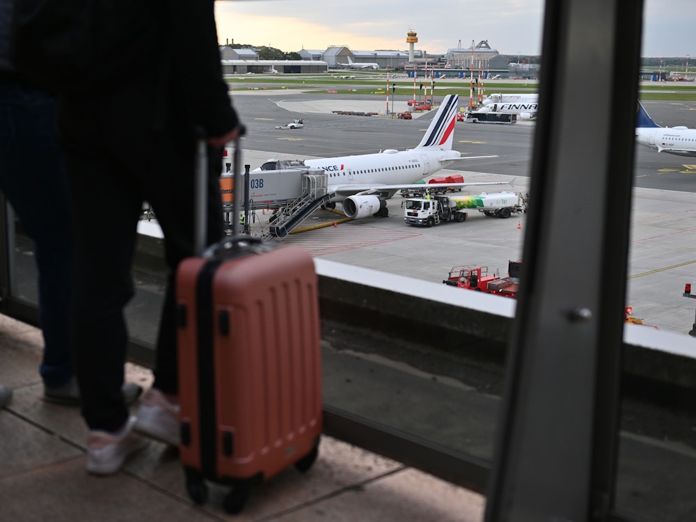 Eine Frau steht im Oktober 2022 mit ihrem Koffer auf der Aussichtsplattform und schaut auf das Flugfeld vor dem Terminal 1 am Hamburger Airport.