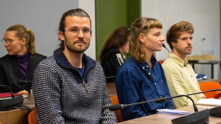 Drei angeklagte Klimaaktivisten sitzen zu Beginn des Eilverfahrens im Gerichtssaal.