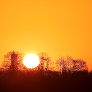 Ein orangegoldener Sonnenaufgang über der Stadtsilhouette mit dem Fernmeldeturm Colonius und dem Dom
