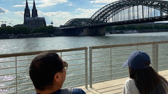 Zwei geflüchtete Jugendliche sitzen am Rhein und blicken auf den Kölner Dom.
