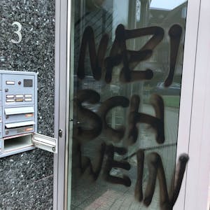 Eine Bürotür, darauf zu sehen in schwarzer Farbe: der Schriftzug „Nazischwein“.