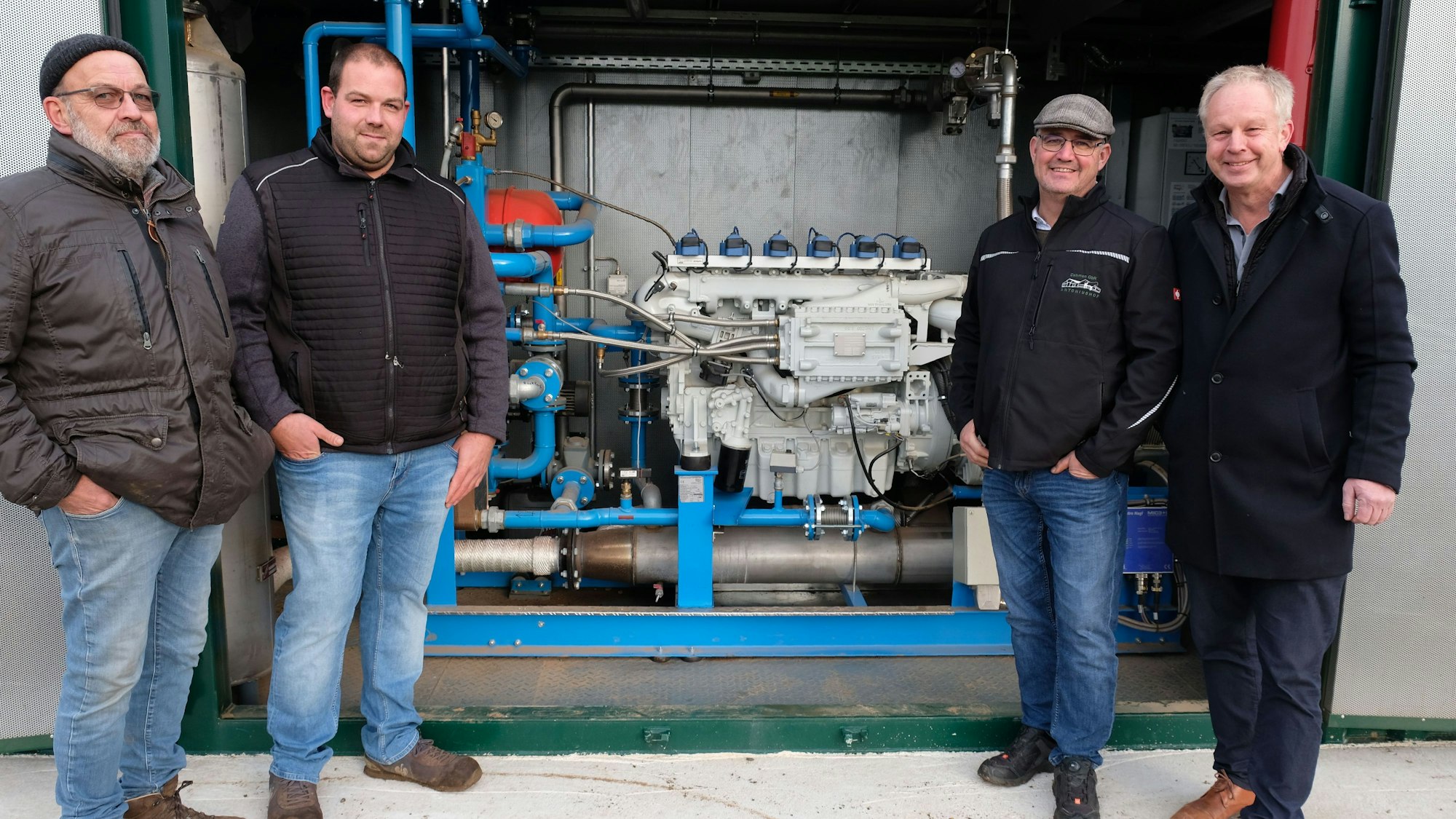 Hans-Josef und Andreas Thelen mit Helmut Dahmen und Heinrich Weidenfeld vom Kreis-Bauernverband vor dem Blockheizkraftwerk der Biogasanlage.