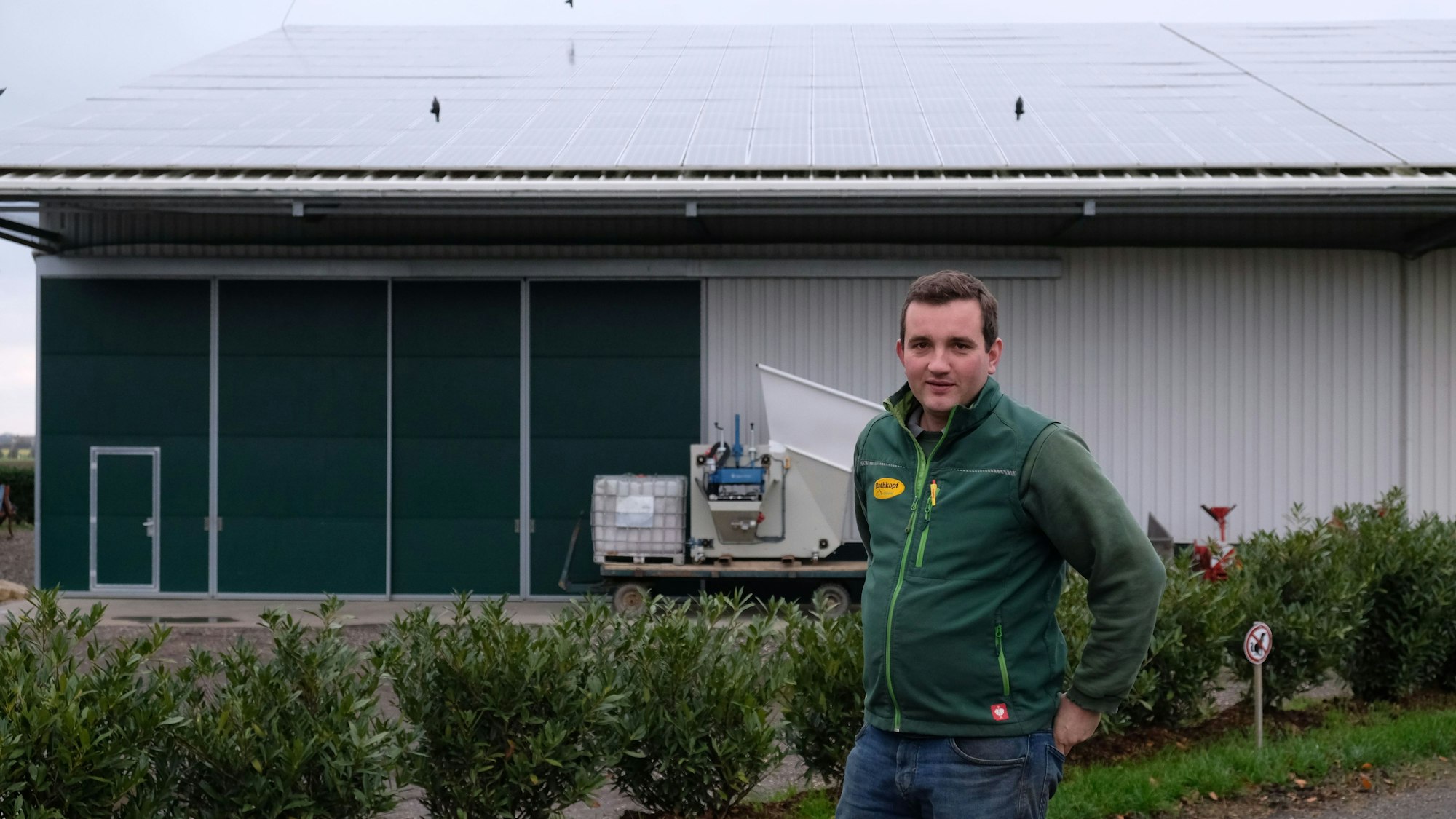 Landwirt Maximilian Rothkopf aus Dom-Esch zeigt die Photovoltaik-Module auf dem Dach eines Betriebsgebäudes.