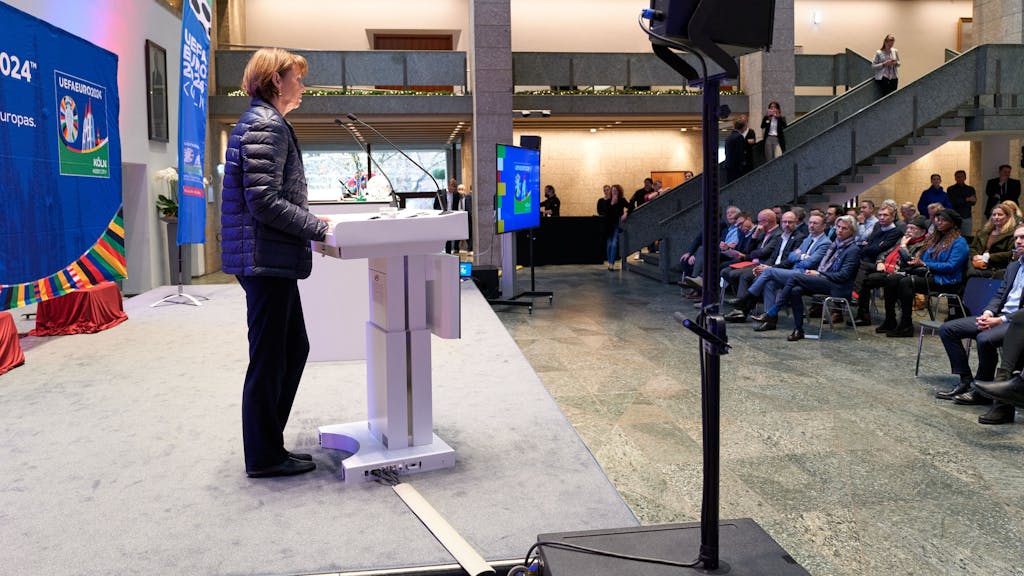 Henriette Reker steht am Rednerpult und hält vor Gästen der UEFA in Köln eine Rede.