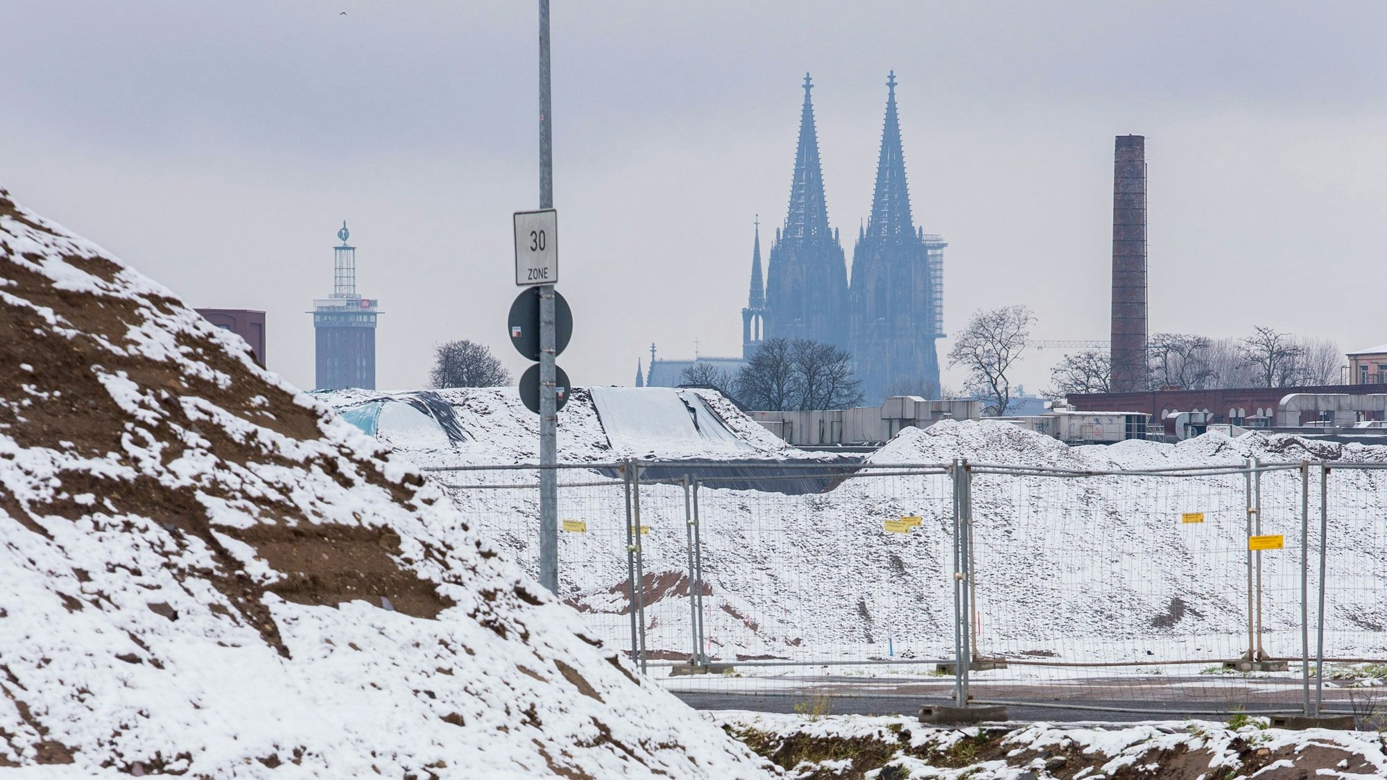 Der Kölner Dom schimmert hinter einer schneebedeckten Landschaft.