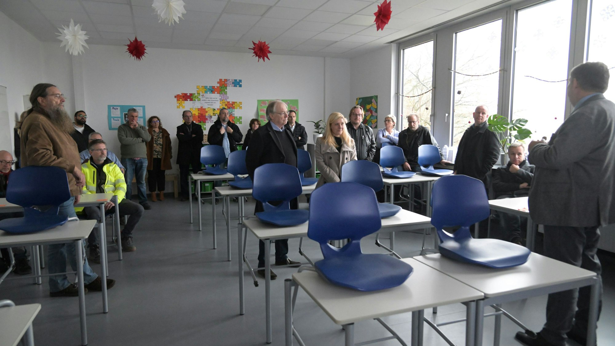 In einem Klassenraum stehen die Gäste der Führung durch das Rösrather Schulzentrum und hören einem Referenten zu.