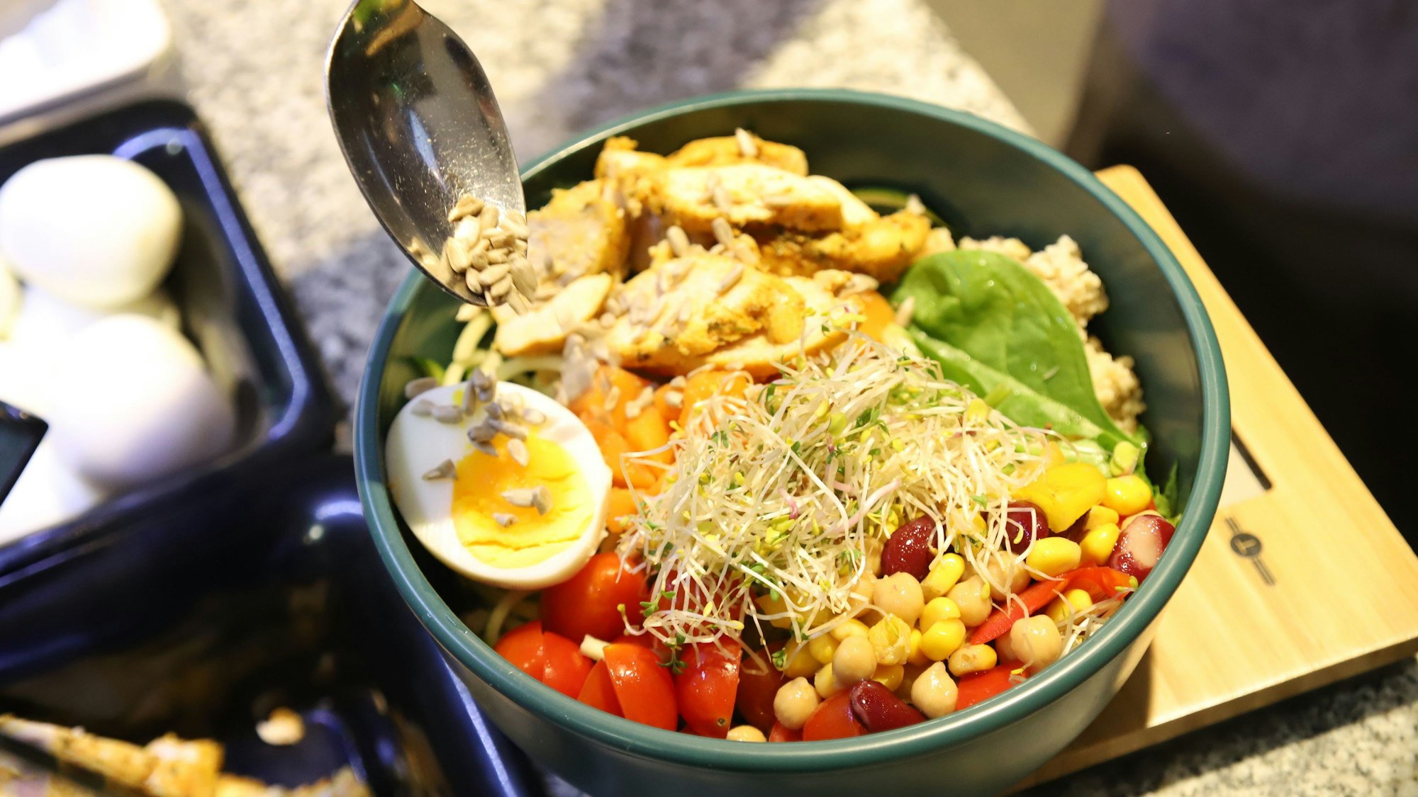 Eine Schüssel mit einem halben gekochtem Ei, Mais, Bohnen, Tomaten und weiterem Salat.