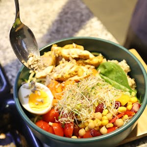 Eine Schüssel mit einem halben gekochtem Ei, Mais, Bohnen, Tomaten und weiterem Salat.&nbsp;