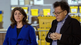 Linda Mai und Detlef Gysan stehen in einem Warenlager bei einer Pressekonferenz.