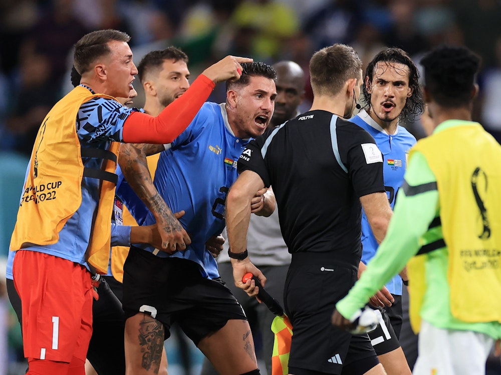 Nationalspieler Uruguays umzingeln den deutschen Schiedsrichter Daniel Siebert nach dem WM-Gruppenspiel gegen Ghana (2:0).
